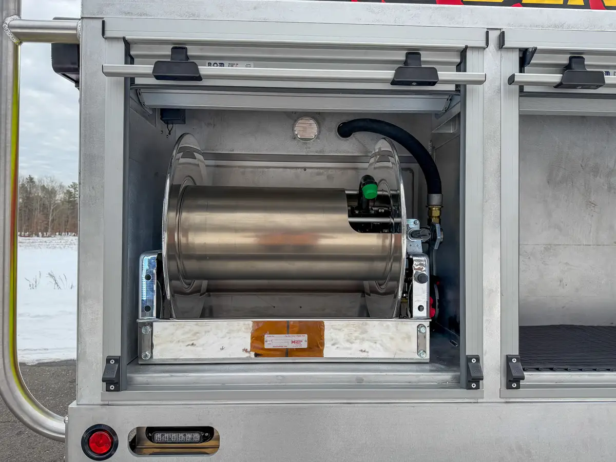 Open side bay with mounted cylindrical tank and hose reel hardware.